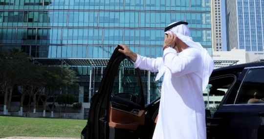 Middle Eastern Businessman fixing his kandoura next to the car|-