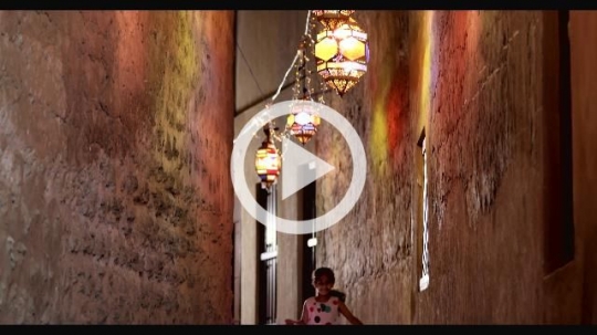 Young Arab girl running through the alleyway decorated by Ramadan Lanterns|