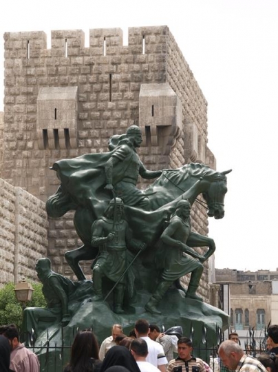 people gathering around the statue of saladin