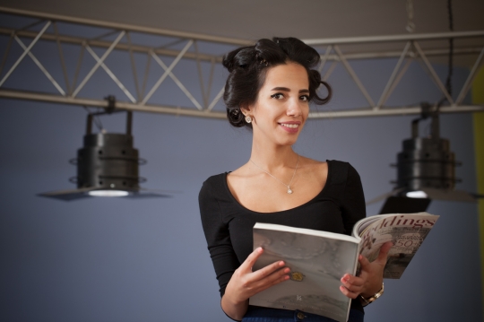 Middle Eastern woman standing with a magazine in her hand|