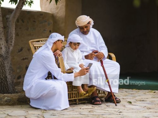 Kids sharing content on mobile with grandfather|-