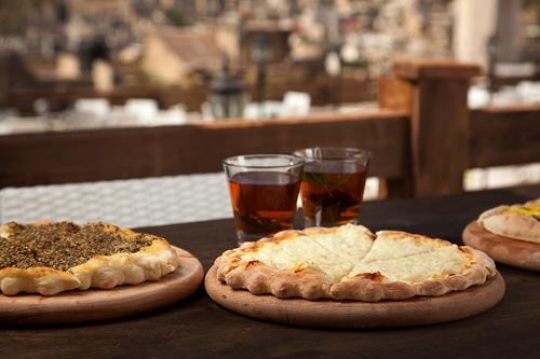 two cups of tea with a pizza and manakish cheese