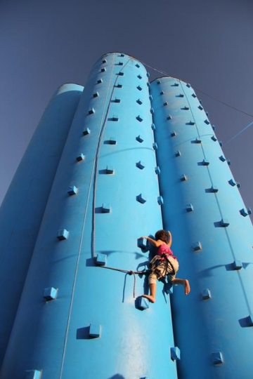 Girl belaying rope, climbing on a very high rock climbing wall.