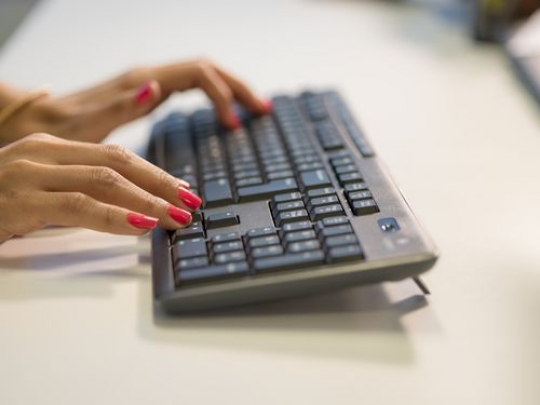 Woman sitting by her desk typing on the keyboard|