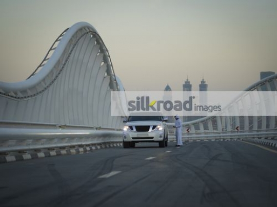 Arab man standing by the car using his mobile|