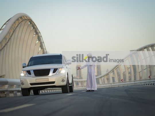 Arab man dressed in the traditional UAE attire talking on the phone|