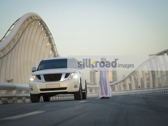Arab man dressed in the traditional UAE attire talking on the phone|