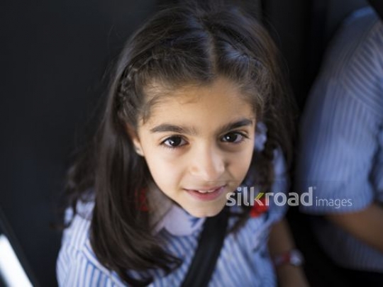 Middle Eastern girl sitting down wearing her seatbelt|-