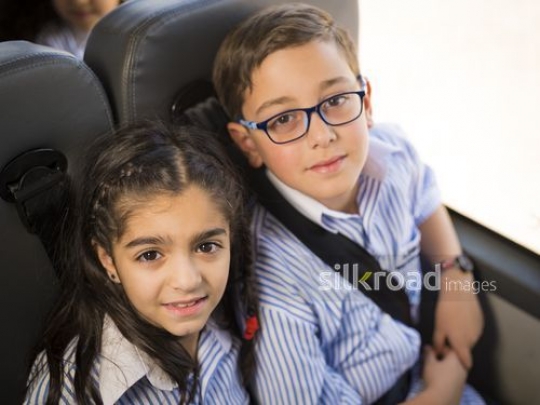 Middle Eastern Kids sitting down together on the bus|-