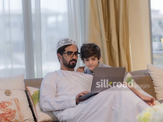 Arab man and young boy sitting together on the couch|