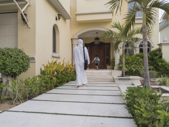 Arab father and son walking towards the house|-