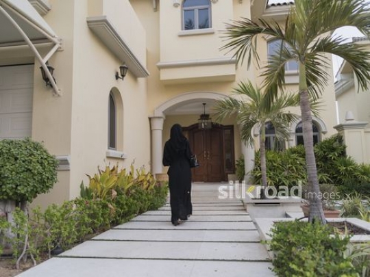 Middle Eastern woman walking towards her home|