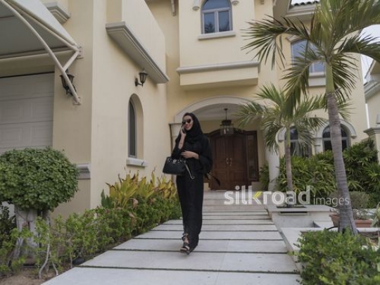 Middle Eastern woman walking outside talking on the phone|