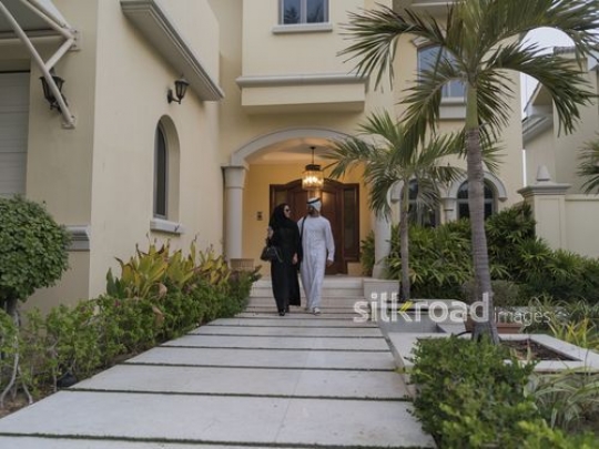 Middle Eastern man and woman leaving the house together|