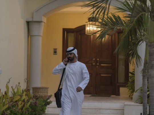 Arab man talking on the phone while leaving his house|-