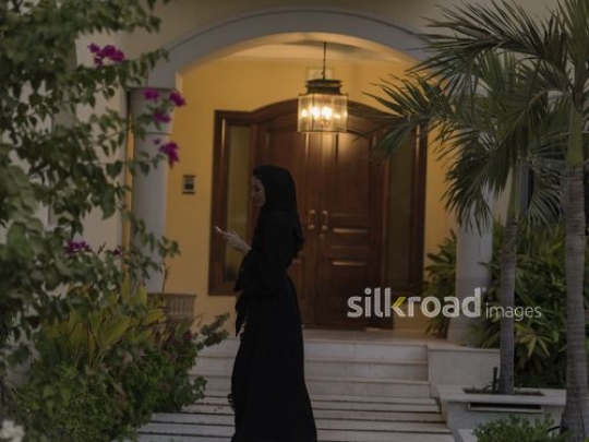 Middle Eastern woman on her phone walking away |