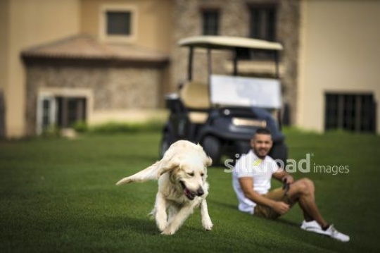 Middle Eastern man sitting down watching the dog run|-