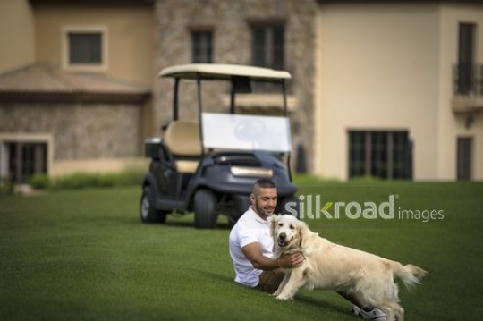 Young Middle Eastern man sitting playing with the dog|-