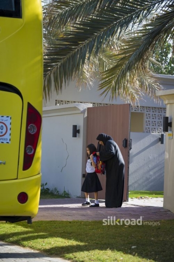 Middle Eastern mother helping her daughter with her school bag|-