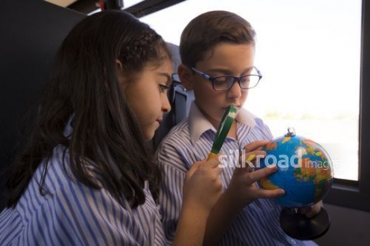 Arab Kids sitting together on the bus looking at the globe|-