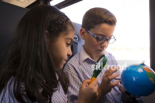 Arab kids sitting together looking at the globe|-