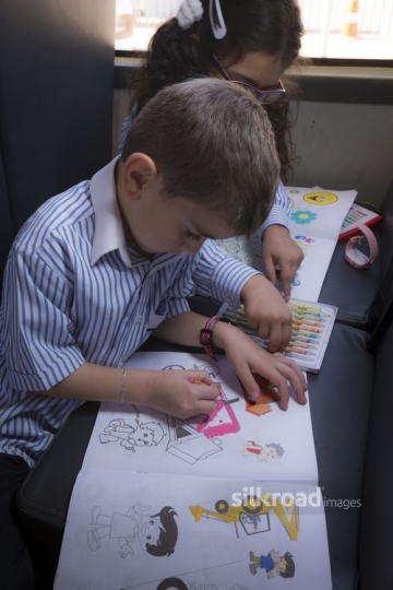 Middle Eastern kids sitting together and colouring |-