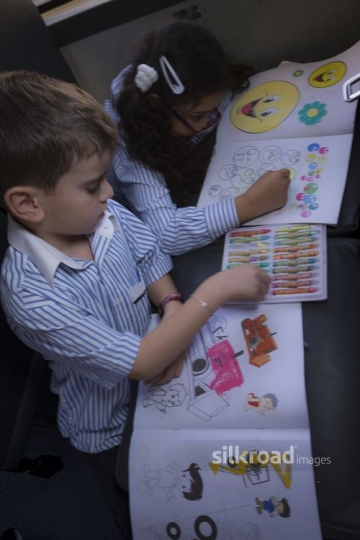 Middle Eastern kids sitting together coloring in their book|-