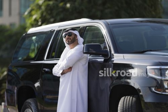 Middle Eastern Businessman standing next to the car with his arms crossed|-