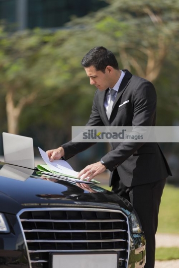Arab Businessman working from laptop outside|