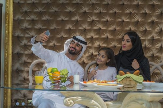 Arab parents taking a photo with their daughter|-