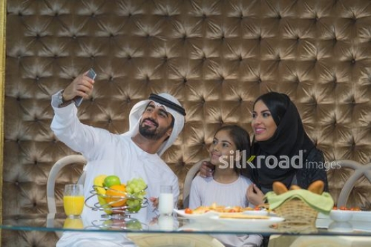 Middle Eastern man and woman taking selfie with their daughter|