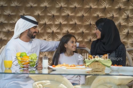 Arab man and woman sitting with the little girl during breakfast|