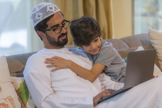 Arab father sitting with his son on the couch|-