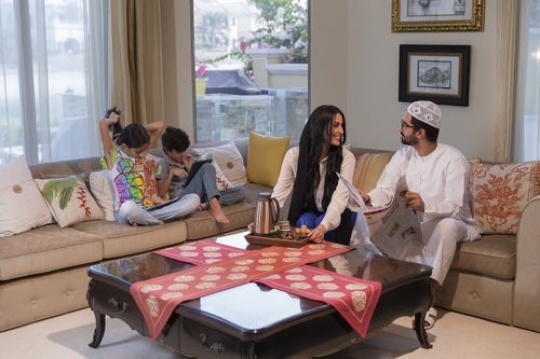 Arab parents sitting with their kids on the couch|-