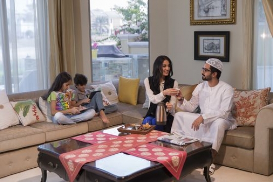 Middle eastern family sitting together on the couch|-