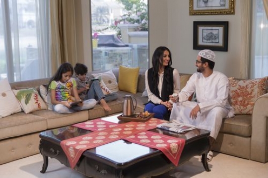 Arab family sitting on the couch together |-