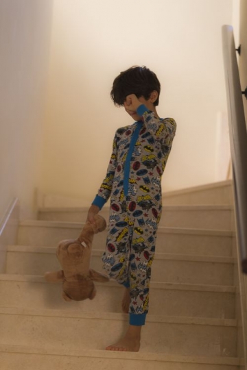 Young boy in his pyjamas walking down the stairs|-