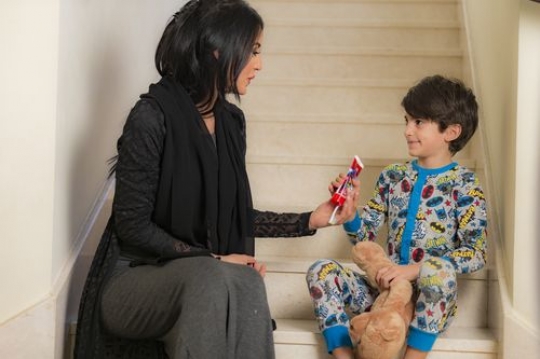 Arab woman giving her kid his toothbrush|-