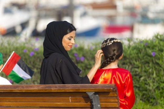 Arab mother helping her young daughter wear the traditional gold head jewellery|-