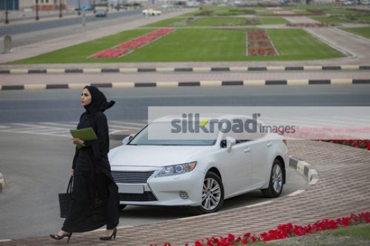 Businesswoman carrying folders and a handbag walking to the office|