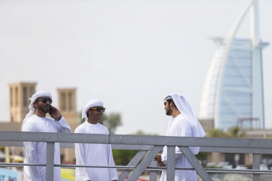 Arab men standing by the dock taking to each other while one man is having a phone call|
