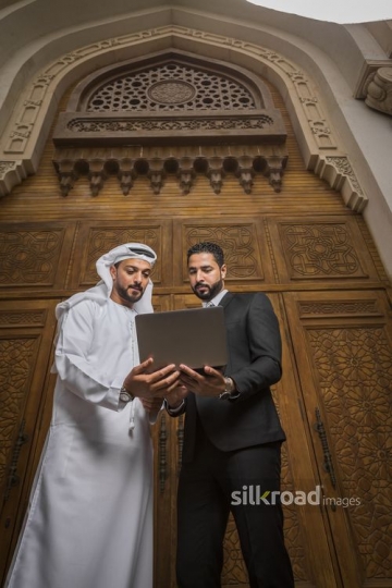 Businessmen standing together using the device|-