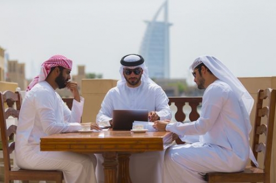 Arab business men sitting outside during a meeting with a background of well-known landmark|