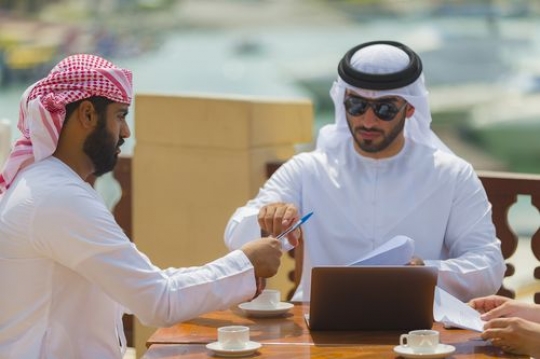 Man handing pen to another man during a business meeting|