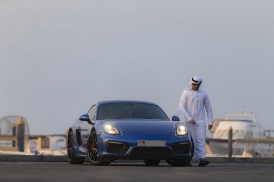 Arab man dressed in traditional attire wearing his sunglasses and leaving his vehicle|-