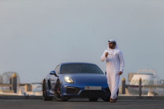 Middle eastern man dressed in the UAE traditional attire moving away from vehicle|-