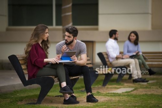 University Students sitting on the bench talking to each other|-