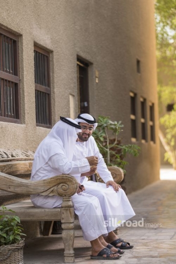 Arab father and son sitting together on the bench|-