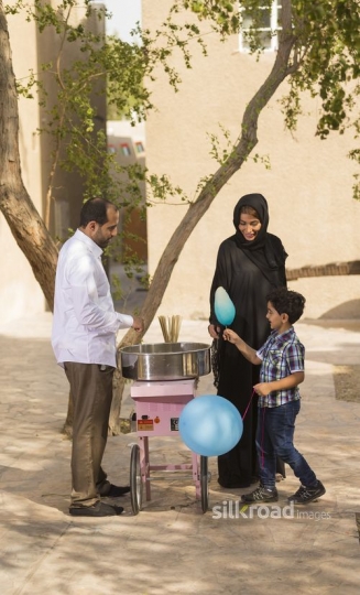Arab mother and boy getting cotton candy from the man|-
