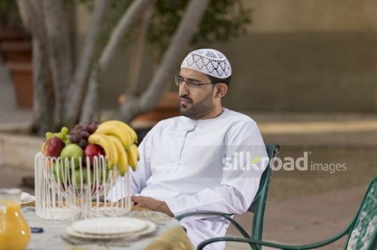 Arab man sitting down|-